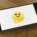 black flat screen tv turned on displaying yellow emoji